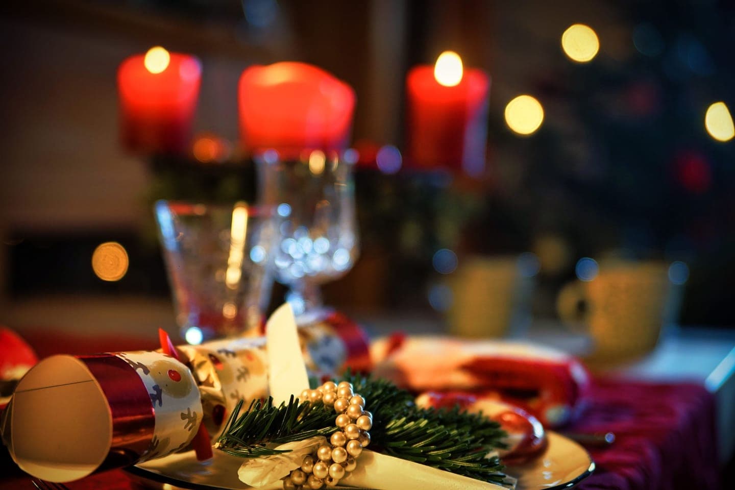 A Christmas table laid with candles, crackers and glasses