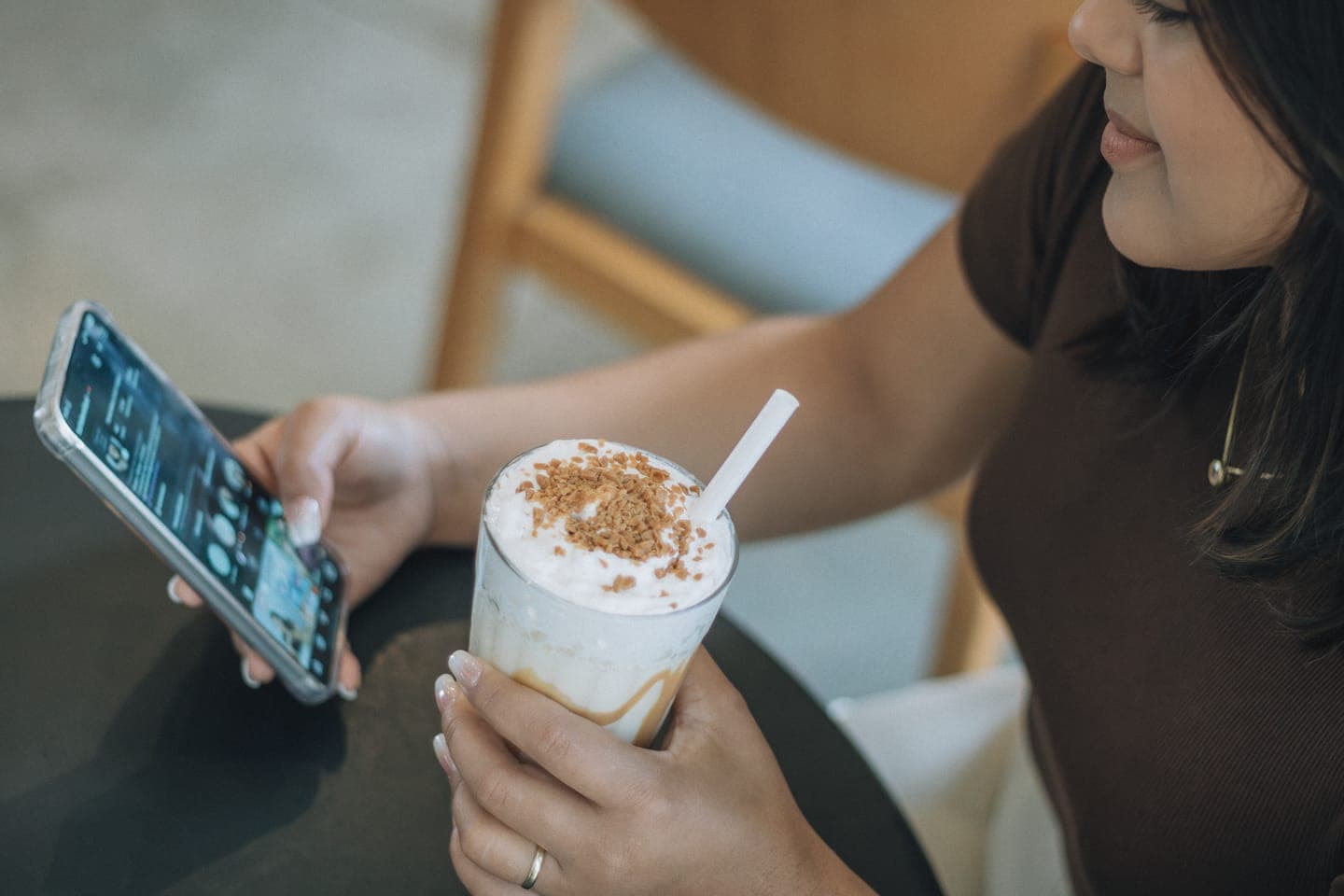 A woman holding an iced coffee while reading her phone