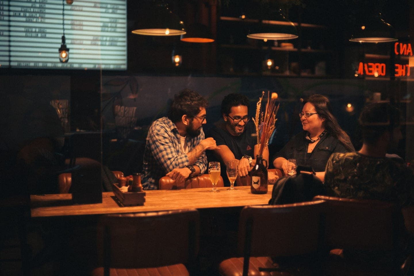 Friends gathered around a table in a dimly lit pub