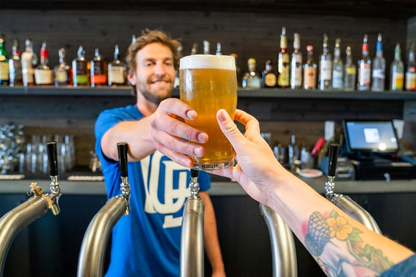 A bartender handing a pint across the bar